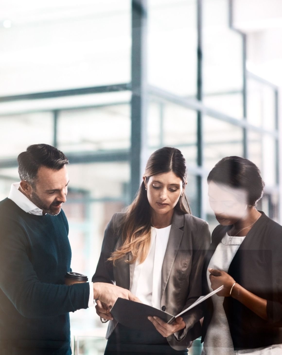 three people looking at a book in an office setting