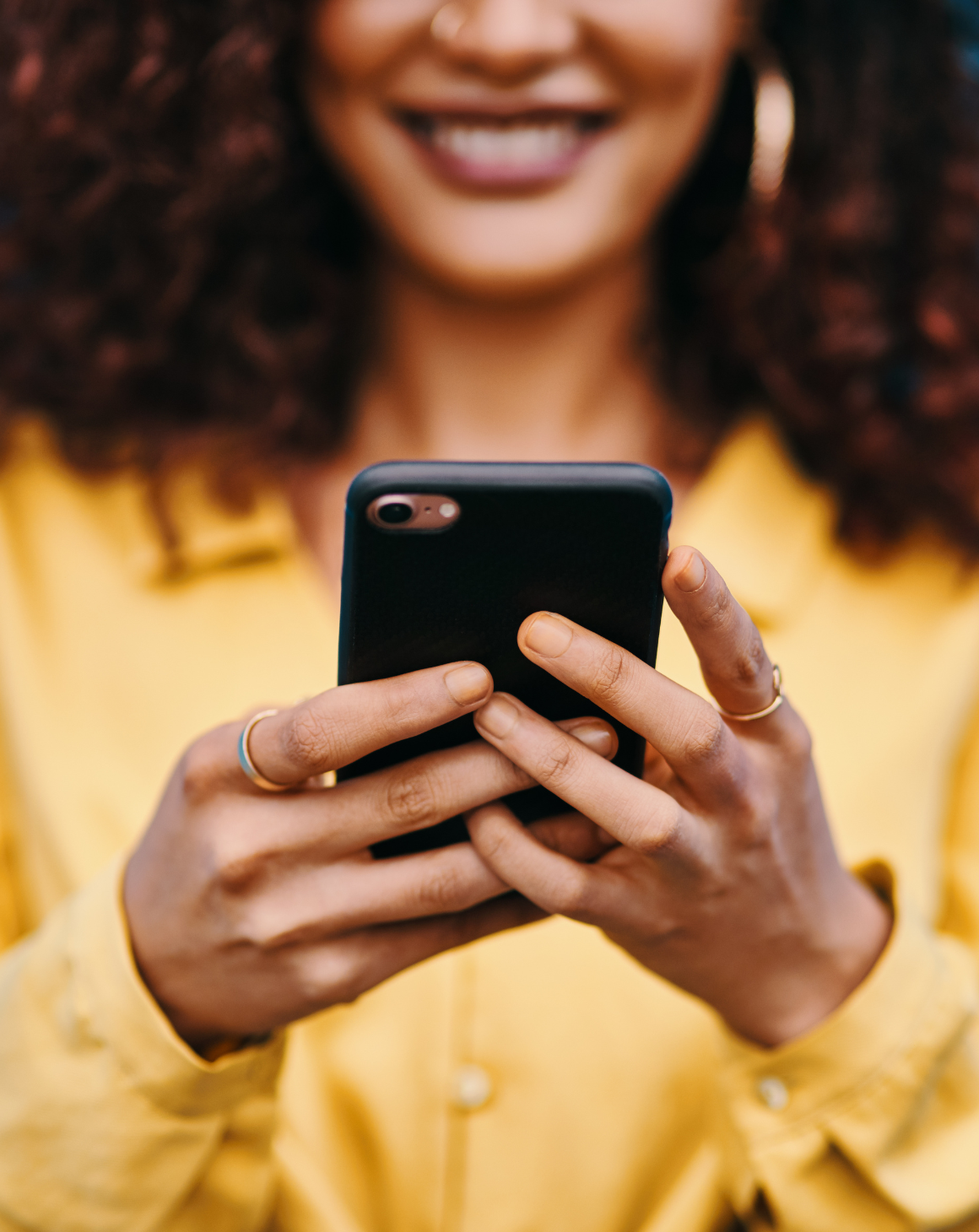 woman-in-yellow-holding-phone-in-her-hands