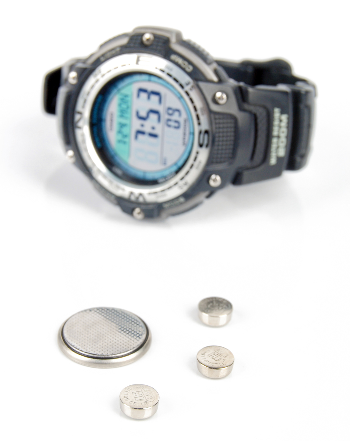 wrist watch and coin and button batteries against a white background