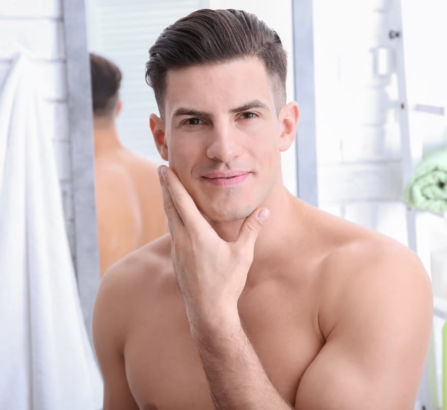 A clean shaved and handsome man standing in a bathroom