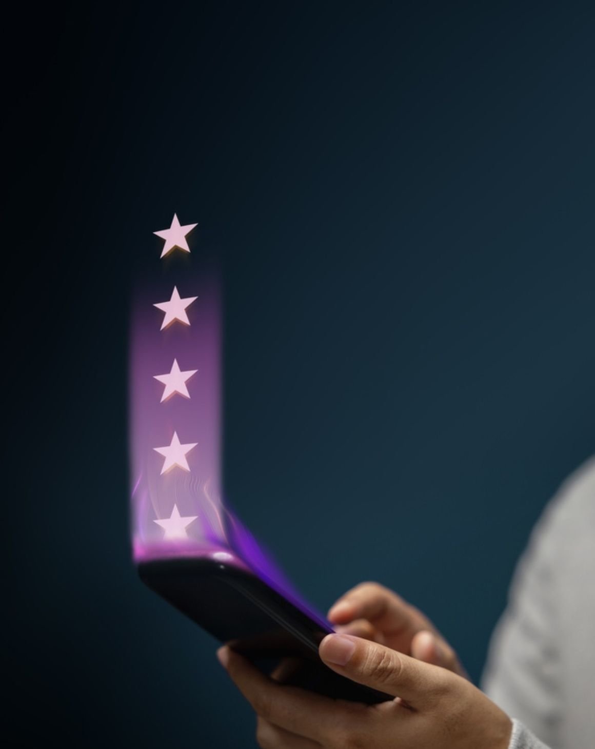 a person holds a smartphone with five glowing stars emerging from the screen