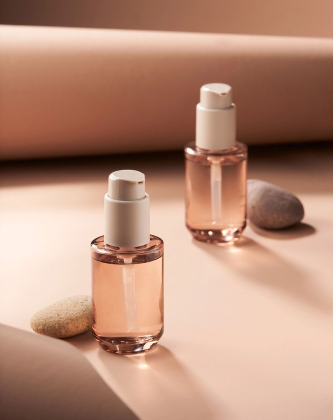 two beauty product bottles against a beige background